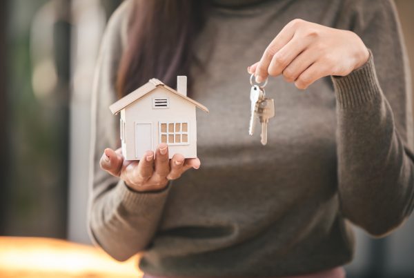 Person holding Keys and a small toy home, signifying the completion of a home purchase