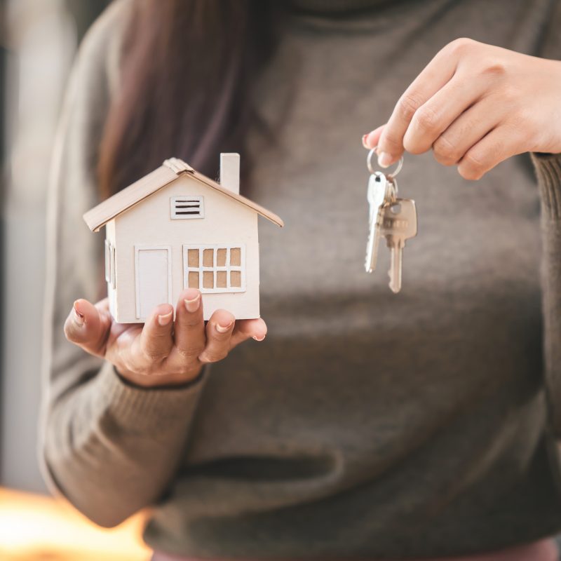 Person holding Keys and a small toy home, signifying the completion of a home purchase