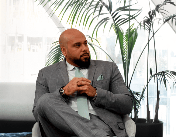 image of Simarjot Singh Judge, the founder of Judge Law, dressed in a smart business suit sitting in-front of a tree.