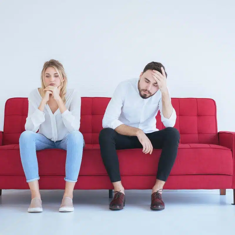 Couple, sitting on a red sofa, considering divorce on Valentine’s Day