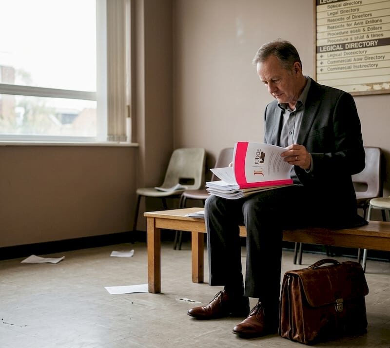Man reviewing documents in tribunal waiting room