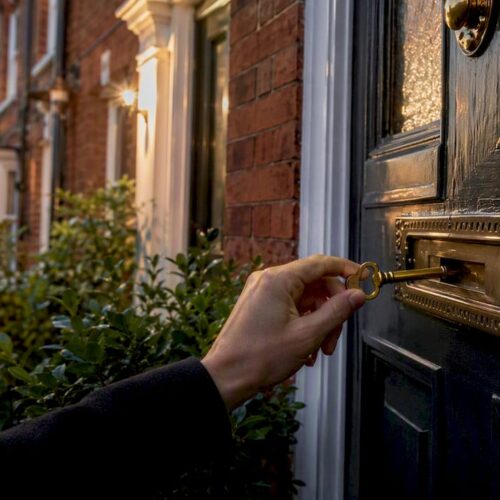 Hand inserting keys into UK red-brick house front door