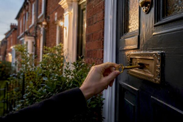 Hand inserting keys into UK red-brick house front door