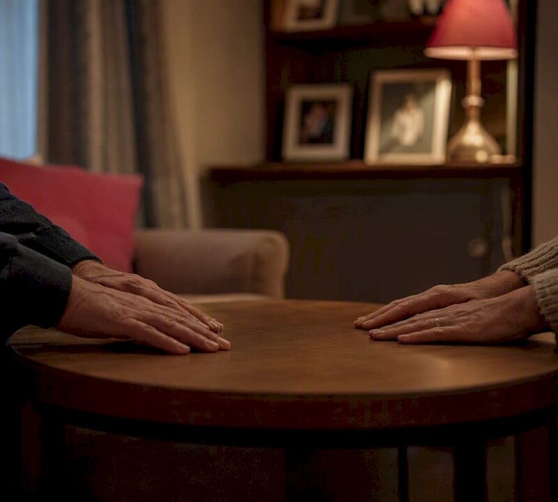 Hands resting on kitchen table in UK home