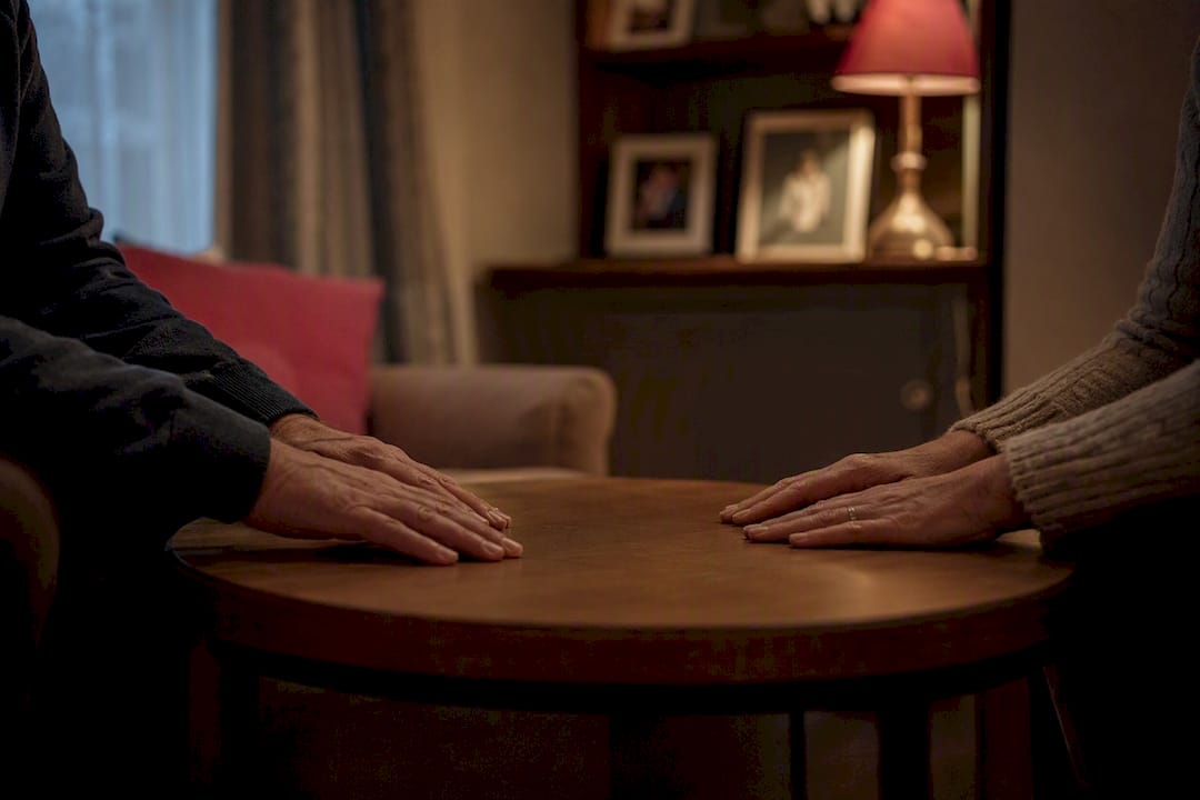 Hands resting on kitchen table in UK home