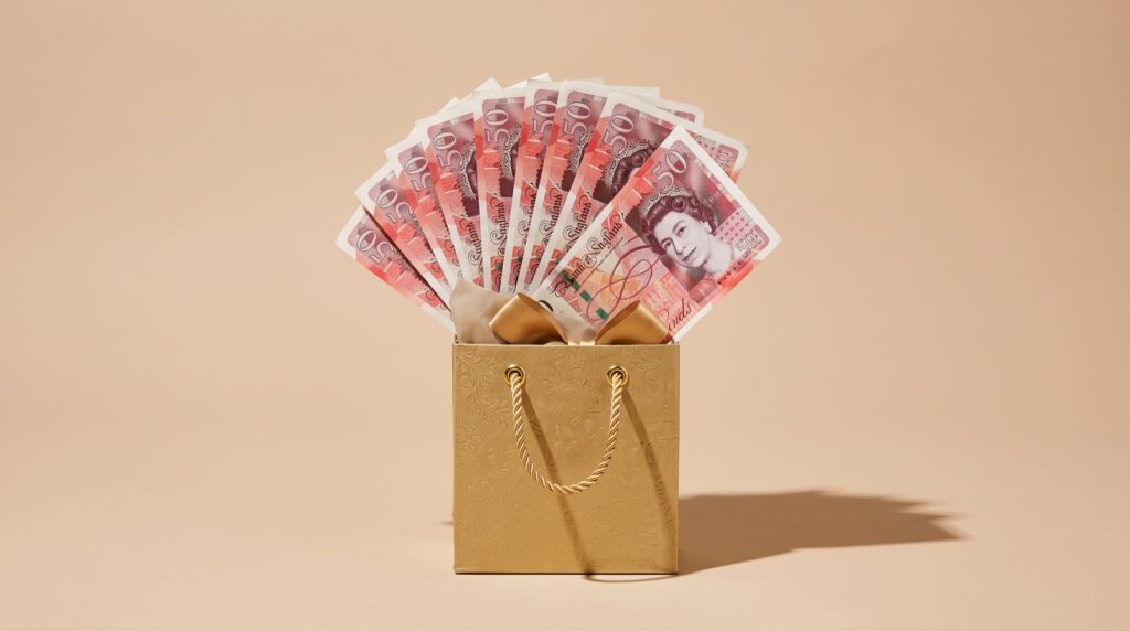 Gold gift bag filled with fanned £50 notes, representing a gifted house deposit from family