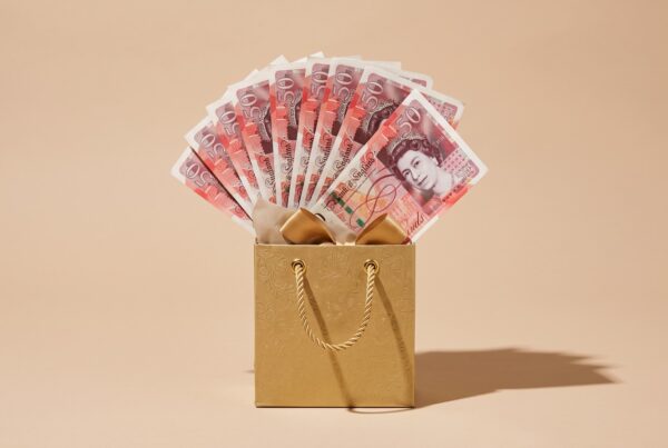 Gold gift bag filled with fanned £50 notes, representing a gifted house deposit from family